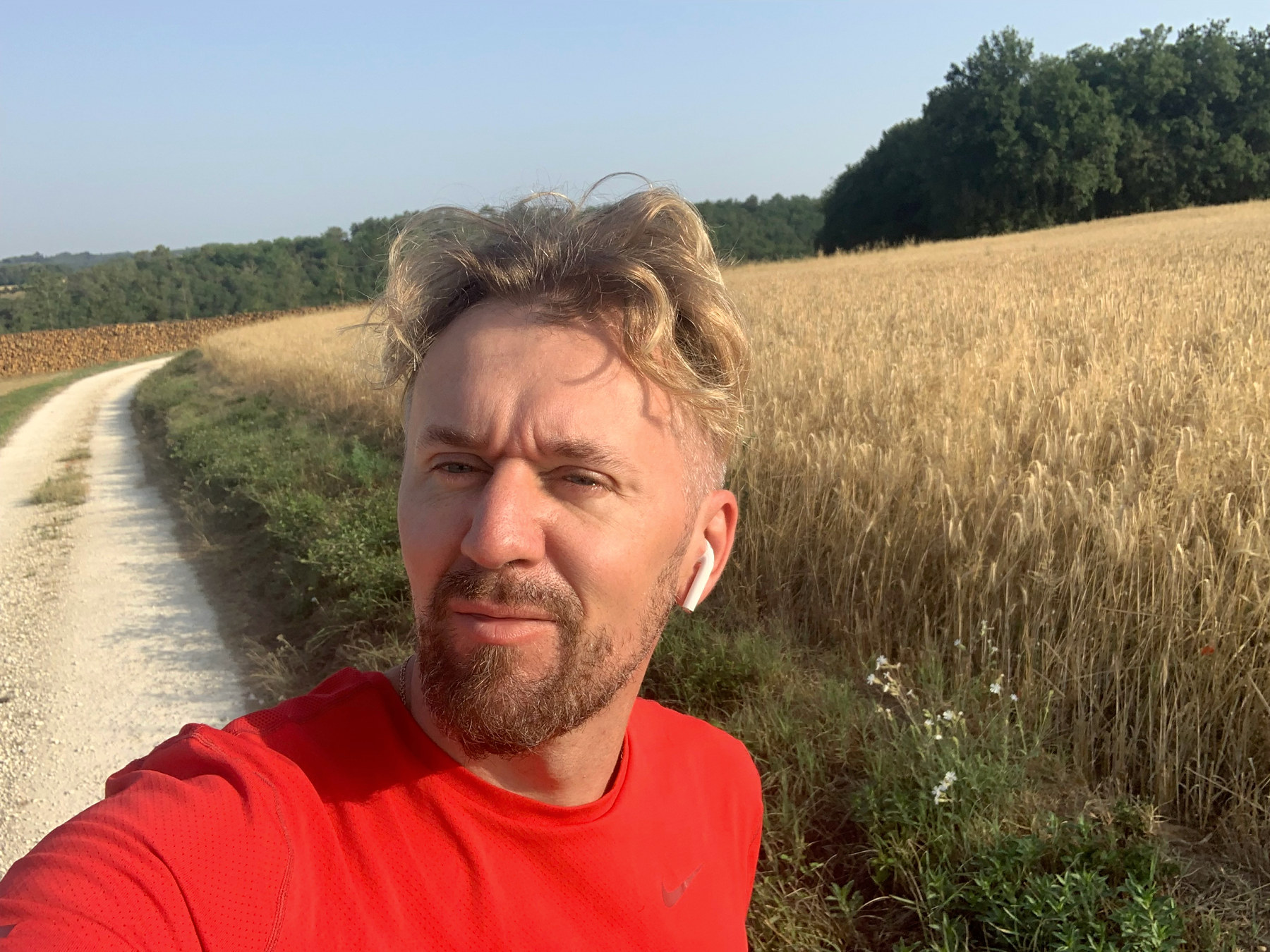 L’auteur en maillot rouge près d’un chemin longeant un champ doré.