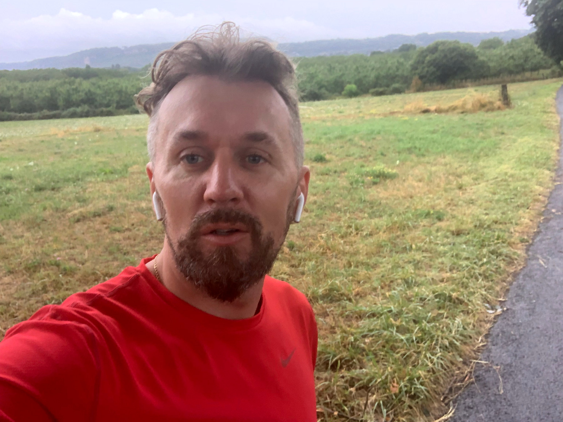 L’auteur en tenue de course, devant un paysage de prés et de collines.