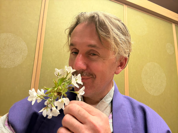 和服姿で白い花の香りを楽しむ男性