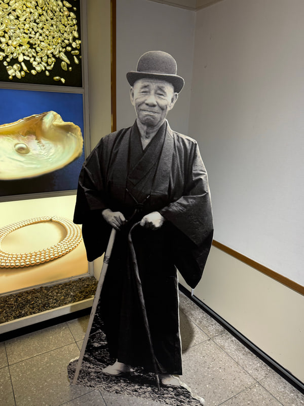 真珠の展示室に置かれた、和服の男性の白黒パネル